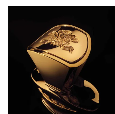 A shiny golden bottle cap with an embossed emblem featuring a crown and wings against a black background.