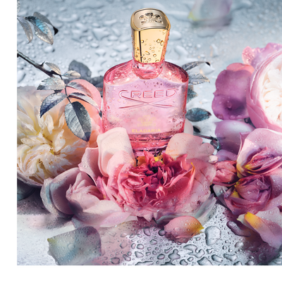 Pink Creed perfume bottle surrounded by roses and water droplets with the text CREED ELADARIA on the bottle.