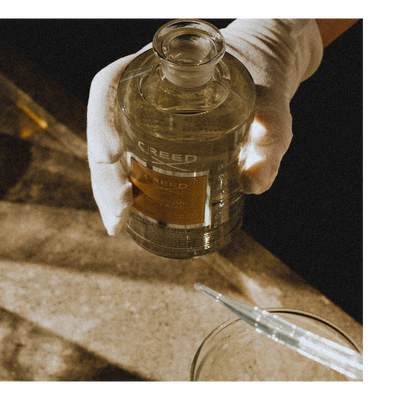 Liquid is poured from a bottle with the text CREE into a beaker containing dark liquid while a pipette is held above.