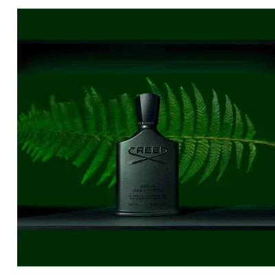 Dark green Creed perfume bottle with a fern leaf behind it featuring the text CREED GREEN IRISH TWEED DE PERE EN FILS DEPUIS 1760 FROM FATHER TO SON SINCE 1760 100 ML 3.33 FL. OZ.
