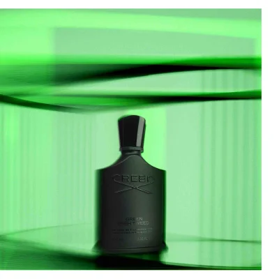 A black bottle of Creed Green Irish Tweed perfume is centered against an abstract green background with text on the bottle that says CREED GREEN IRISH TWEED DE PERE EN FILS DEPUIS 1760 FROM FATHER TO SON SINCE 1760 100 ML 3.33 FL. OZ.
