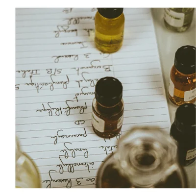 Small glass bottles containing liquids sit on a sheet of paper with handwritten notes including 3 Resorcin Citronellol Linalool Paracresol CD Phenylactique muguet Eucalyptus Phénylacétique 5 Bergamot 3 Ris Italia S/B Jakon th benzyle 24 NCE.