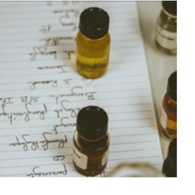 A close-up view shows two small glass vials with black caps, one with yellow liquid and one with dark brown liquid, placed on a ruled notebook page displaying handwritten notes with the text: 15, 3 Raud, Borgon S/B IT, CD, peremya.
