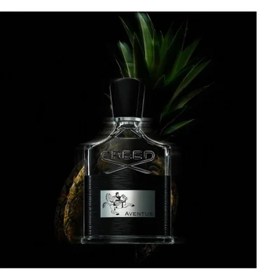 A bottle of Creed Aventus perfume with a black cap and textured label, featuring a silver emblem of a man on a horse, stands in front of a pineapple with green leaves against a dark background, displaying the visible text CREED Aventus.